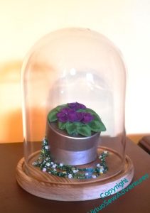 Parlour dome containing a round gold painted trinket box topped by the clump of violets and with the bead necklace spilling out. It's not entirely successful, but suggests a starting point.