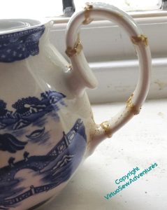 Close up of the handle of a small willow pattern teapot, mended using the "New Kintsugi" style. Rather amateurishly, but it seems solid!