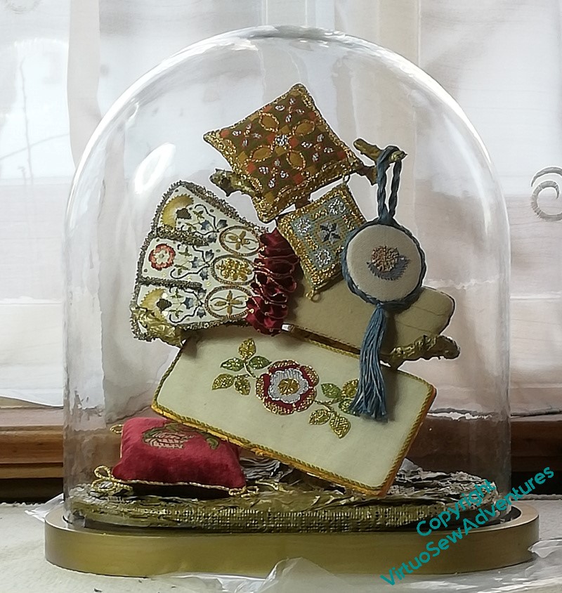 The results of several years of online embroidery classes in Tudor Embroidery, displayed under a glass dome.