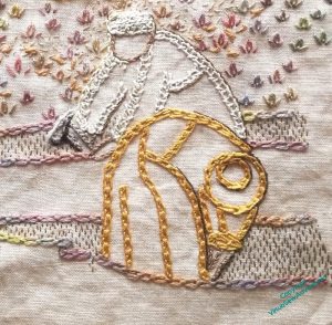 Close up of two embroidered excavators, one in a pale thread with a very square stitch, the other more golden thread, in shel chain stitch.