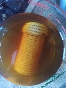 The finished coiled rope pot, submerged in a jug of cold tea.