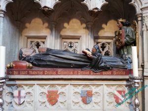 Photograph of Rahere's tomb. An effigy lies on top, with two small figures with books in their hands and an angel at its feet.