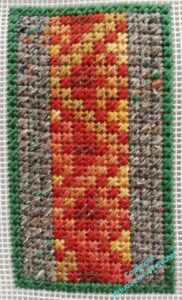 Panel entirely in mosaic stitch, again green around the edge, three columns of grey on each side, and a central panel in shades of orange and brown.
