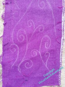 Purple linen like fabric with curlicues drawin on it in chalk