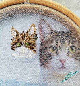 Close of up early progress on the cat's head, with the reference photo seen through the gauze
