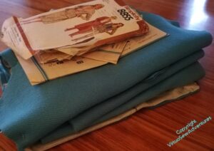 Pile of folded pattern pieces on a varnished table, pattern envelope on top.