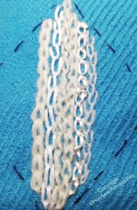Mix of stitches and threads in white and cream on turquoise tweed